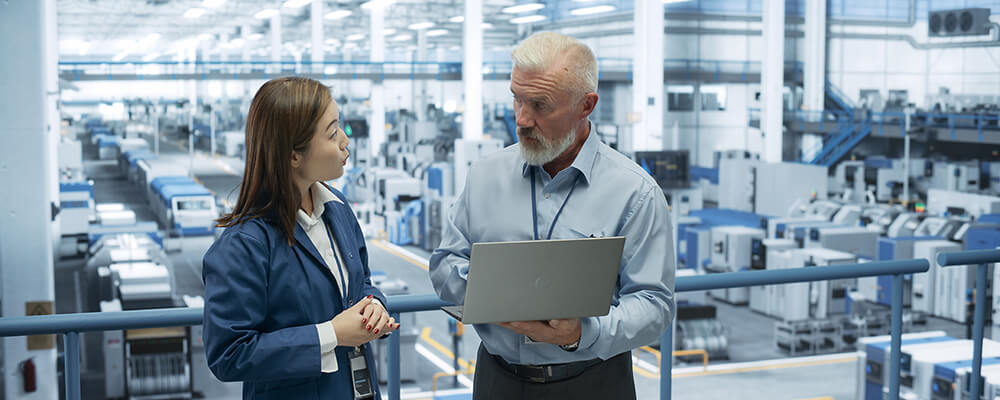 Project manager conversing with plant manager on balcony overlooking the plant floor